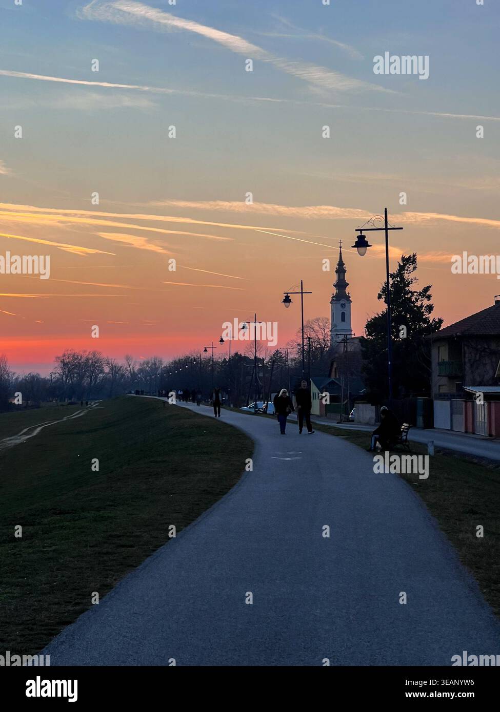 Une promenade paisible au coucher du soleil le long du Danube à Futog, en Serbie, avec des gens marchant et le beau ciel comme toile de fond. Banque D'Images