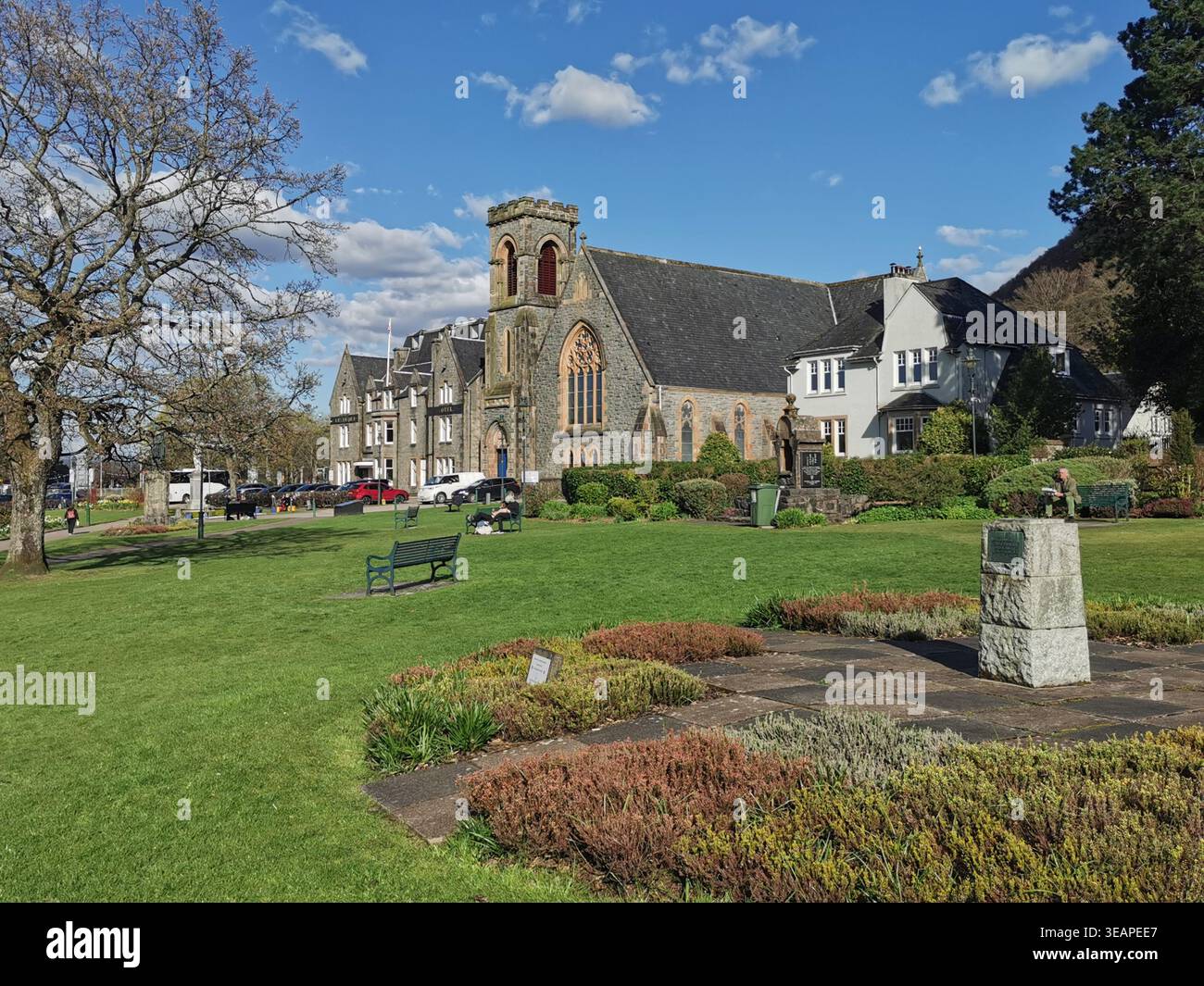 Ensoleillé la parade de Fort William avec l'Alexandra Hotel, l'église de Duncansburgh et les jardins colorés qui brillent dans la lumière de l'après-midi. - Image de stock capturée avec un smartphone