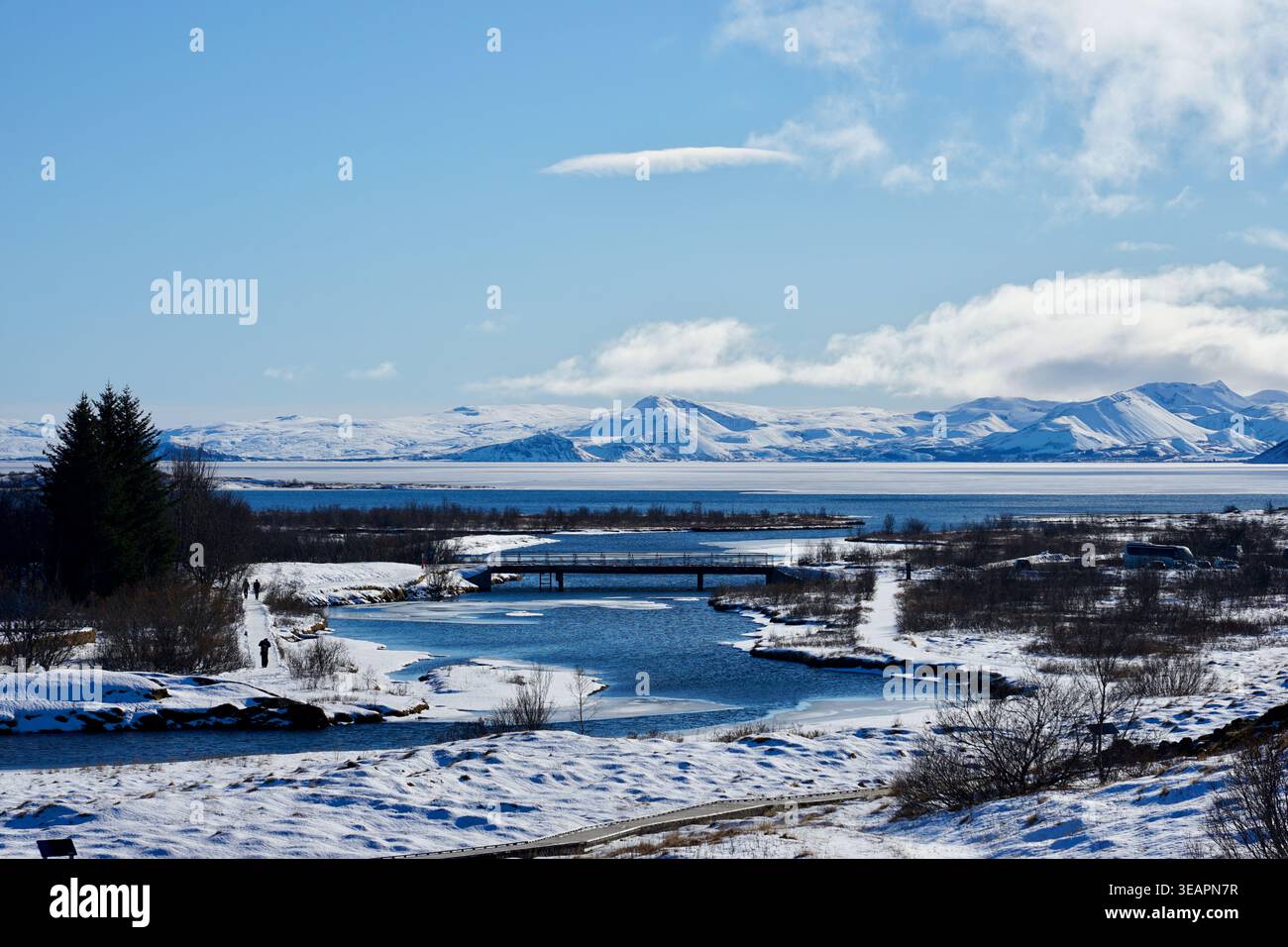 Snowy Winter River et Low Bridge avec lac et montagnes lointaines sous Blue Sky Banque D'Images