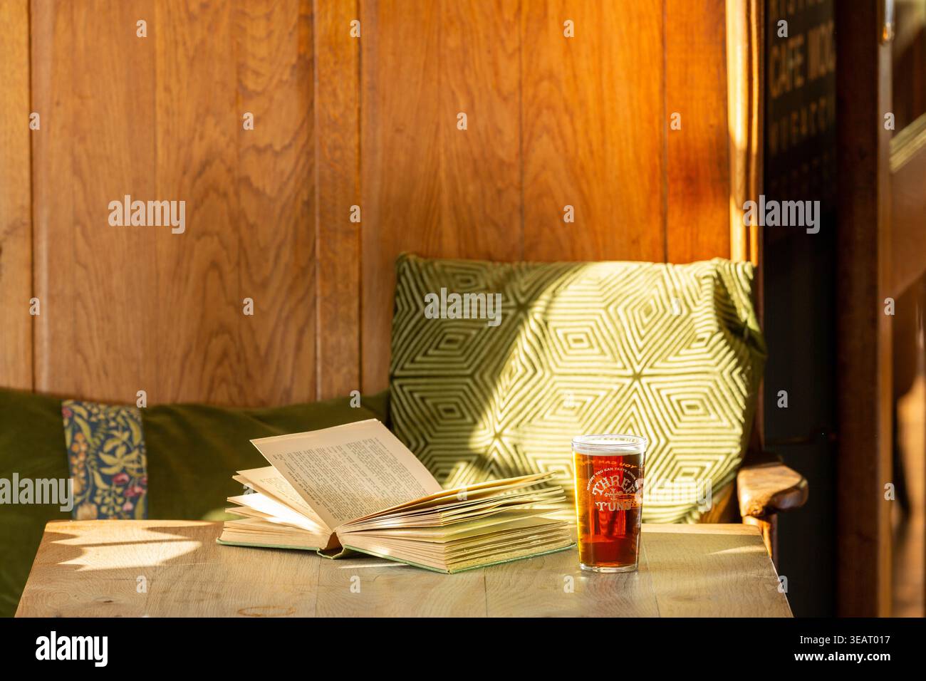 Détente avec une pinte et un livre dans un siège confortable dans un pub britannique Banque D'Images