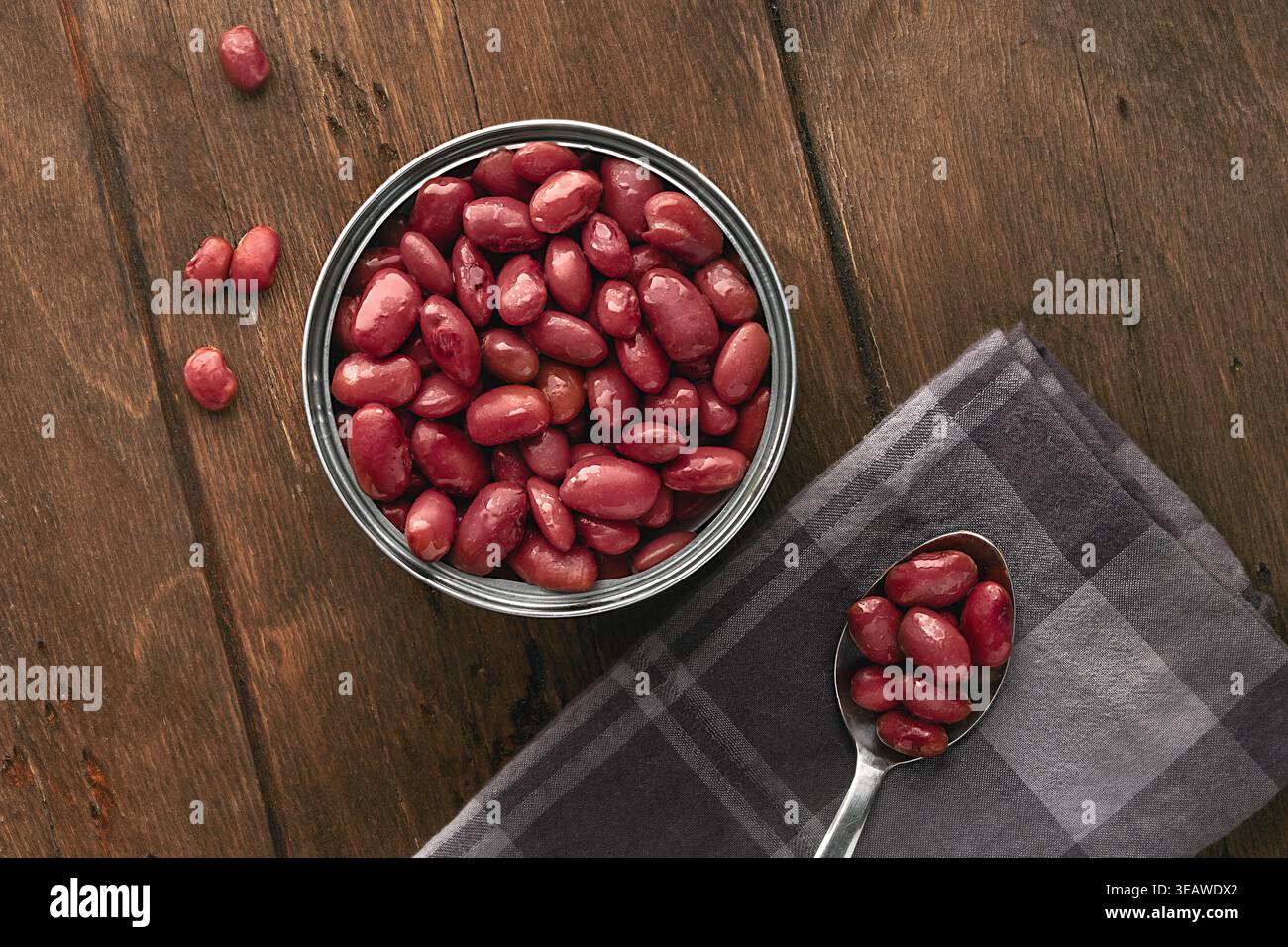 Haricots rouges en conserve servis dans un style rustique minimaliste sur une table en bois dans une boîte de conserve vue de dessus FlatLay. Une boîte de conserve ouverte remplie à ras bord avec Banque D'Images
