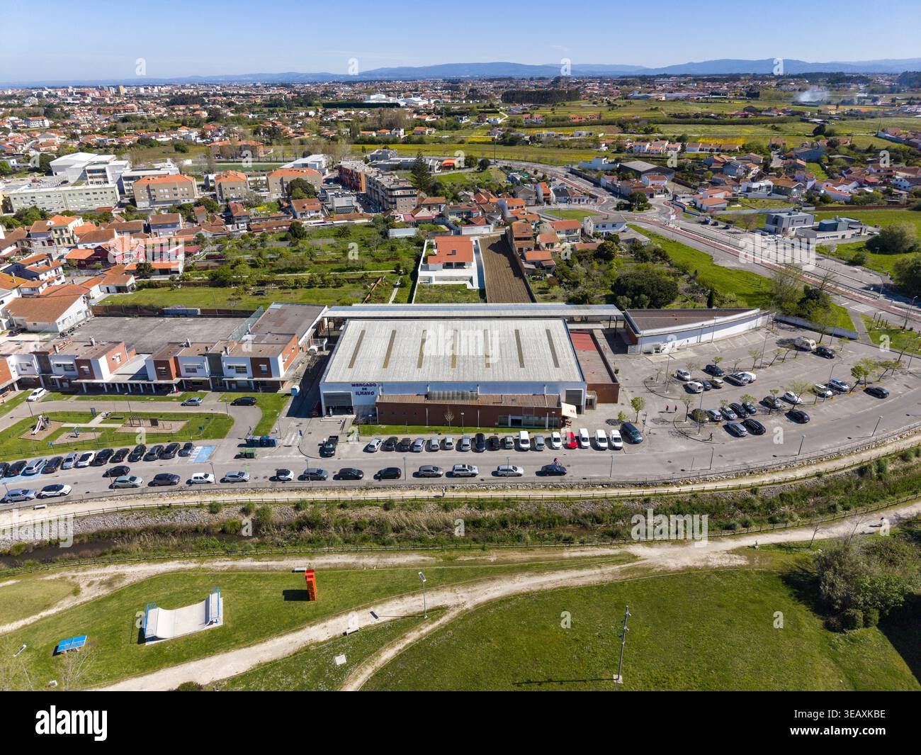 Vue aérienne d'un bâtiment avec un grand parking, entouré de maisons et de champs verdoyants à Espinho, Portugal. Banque D'Images