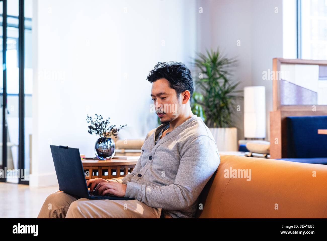 Jeune homme asiatique travaillant sur ordinateur portable dans l'espace de coworking Banque D'Images