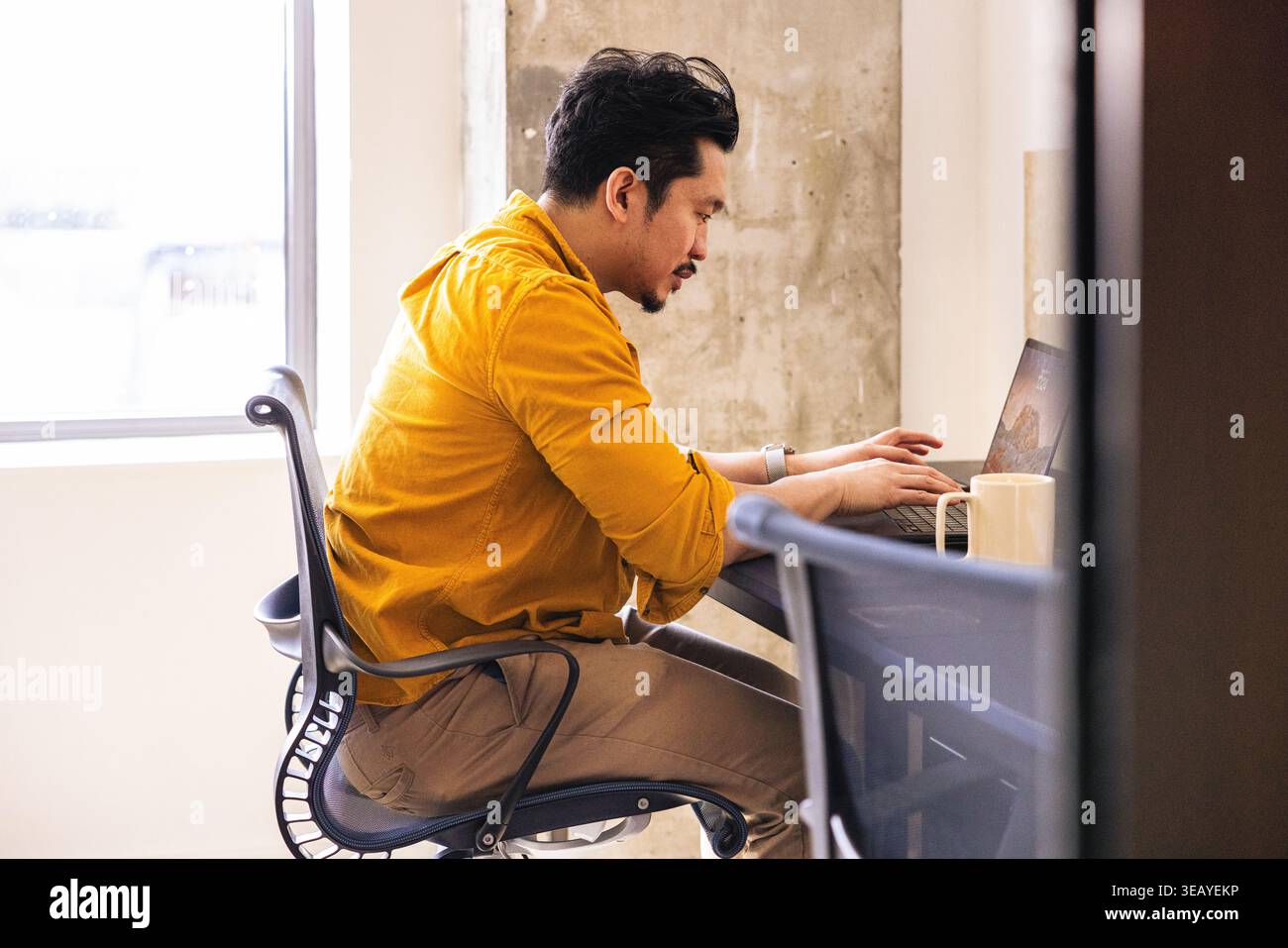 Homme asiatique utilisant un ordinateur portable au bureau Banque D'Images