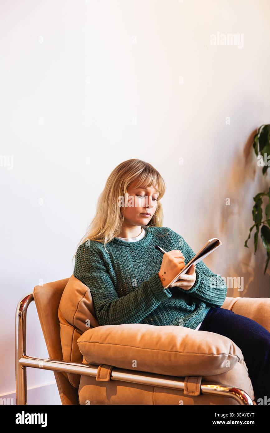 Femme d'affaires occasionnelle caucasienne écrivant dans un cahier Banque D'Images