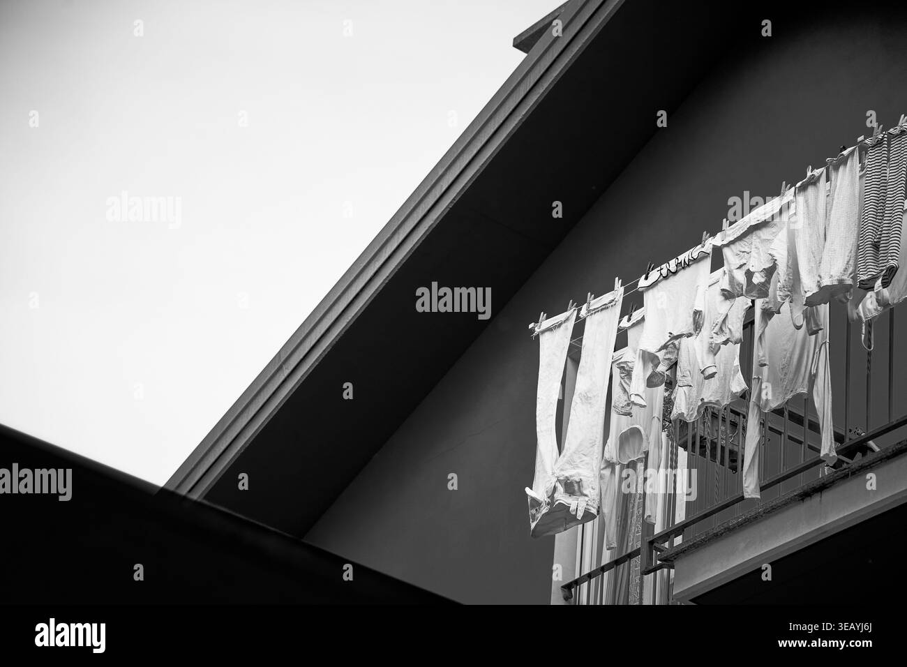 Linge suspendu à un balcon à Chiavenna, capturé en monochrome contre des lignes architecturales géométriques, représentant la vie quotidienne, la simplicité. Banque D'Images