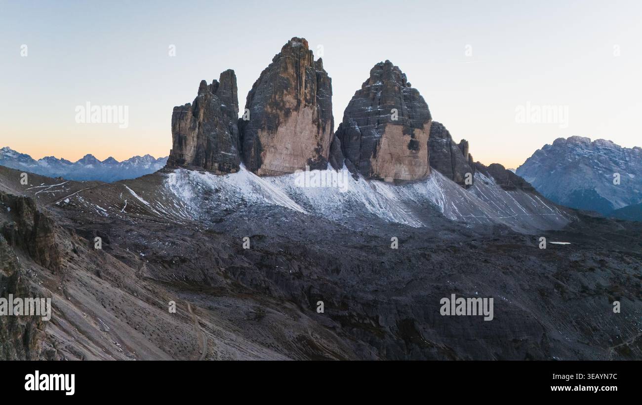 Vue aérienne des majestueux sommets Tre Cime di Lavaredo transperce le ciel, leurs textures robustes contrastant avec la douce lumière de l'aube, Tre Cime di Lavared Banque D'Images