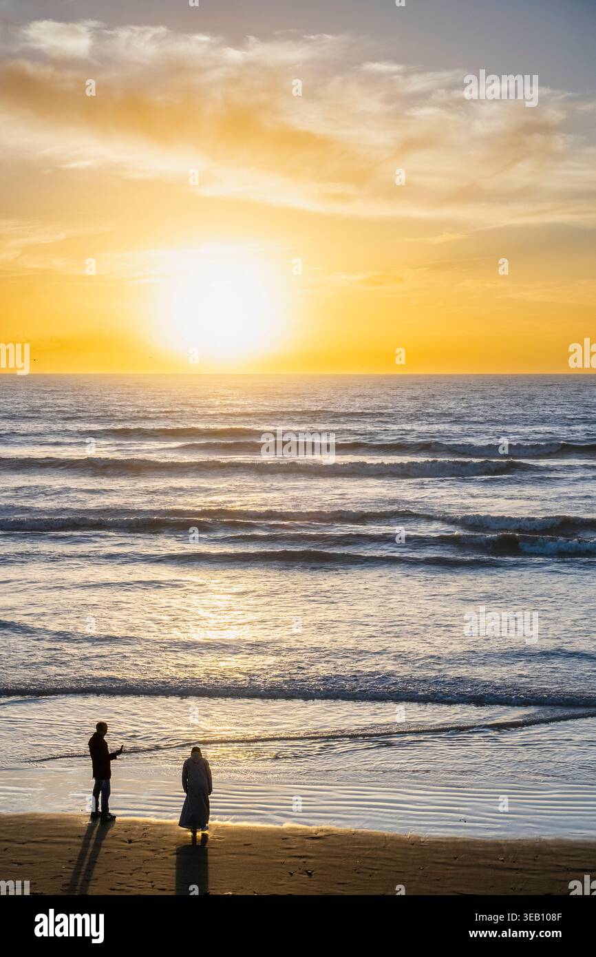 Maroc, plage d'Agadir, coucher de soleil sur la mer, avec le soleil à l'horizon et le ciel dans un ton jaunâtre. Il y a quelques vagues dans l'eau. L'image est Banque D'Images
