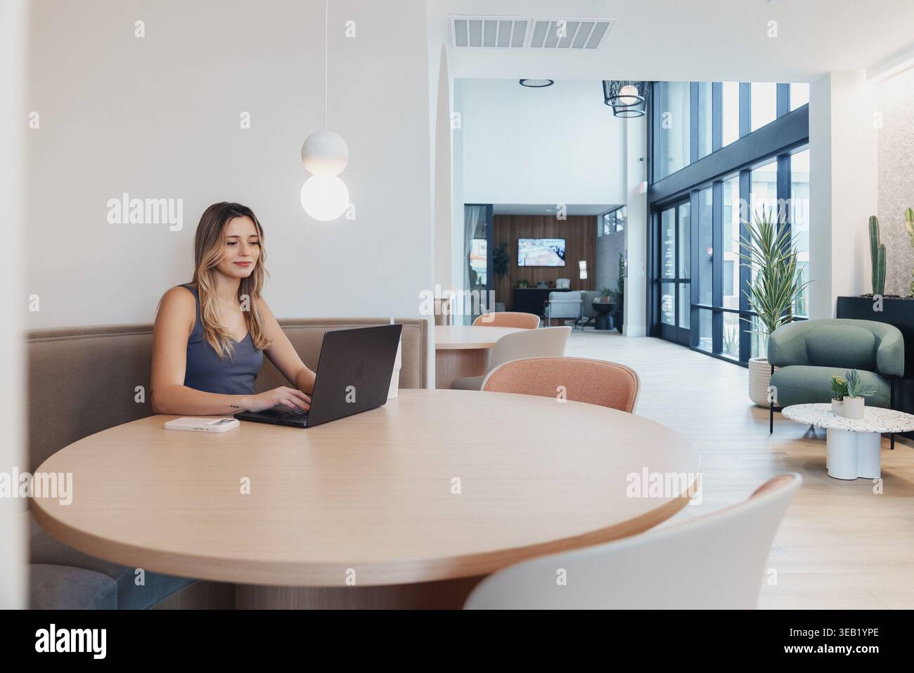 Occupant féminin dans le spacieux salon. Femme appréciant la réunion décontractée dans l'espace lumineux de l'atrium. Individu féminin assis confortablement dans Open communal Banque D'Images