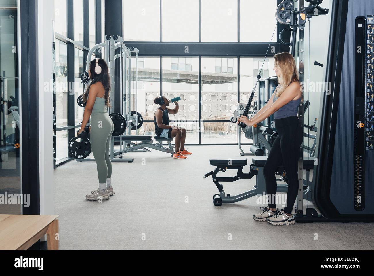 Les femmes s'entraînent ensemble. Deux femmes se concentrent sur la forme physique avec le coaching et l'interaction amicale. Paire de femmes s'entraînant près des câbles avec le formateur Banque D'Images