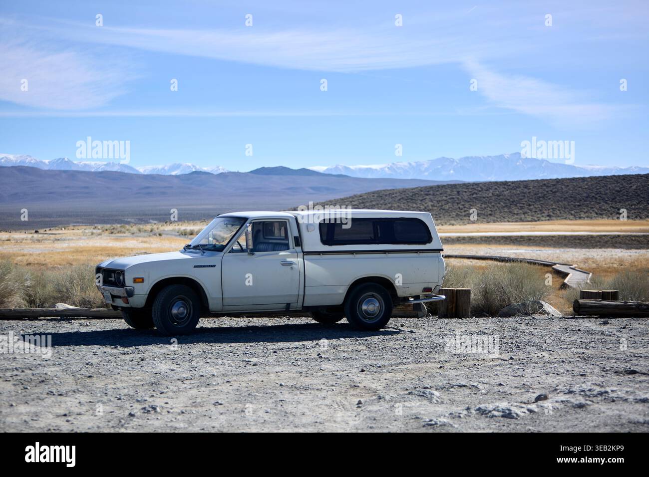Camionnette classique blanche avec coquille de camping-car parcourant le paysage désertique Banque D'Images