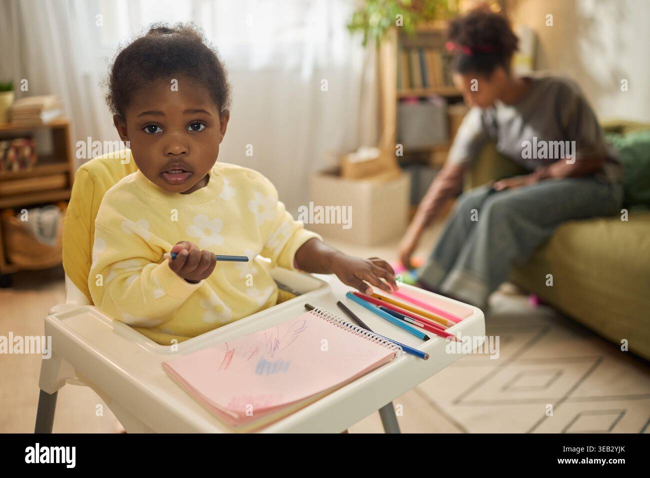 Portrait d'enfant noir dessinant à la maison dans une famille à faible revenu Banque D'Images