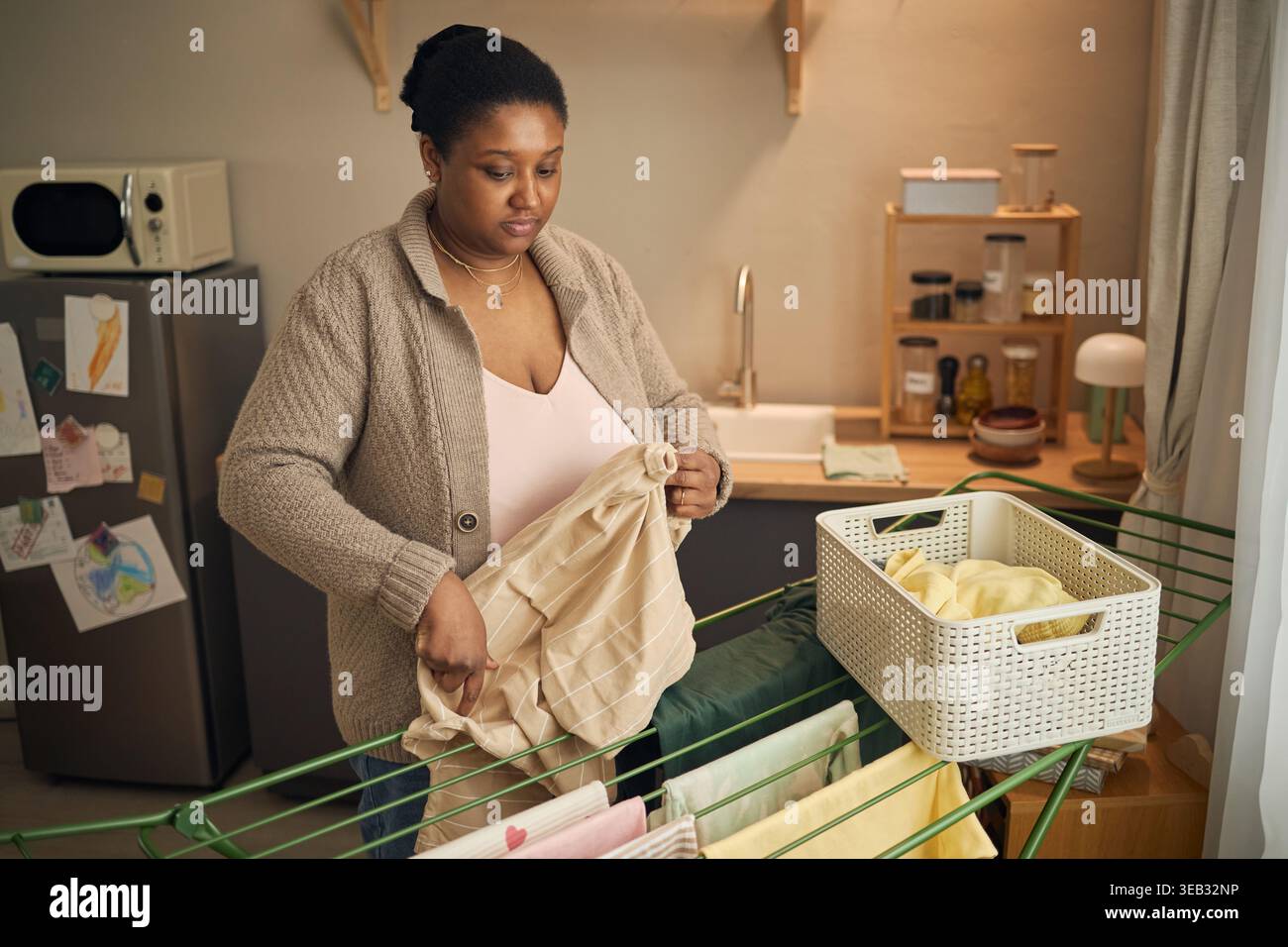 Femme noire séchant la lessive dans le cadre de la maison à faible revenu Banque D'Images