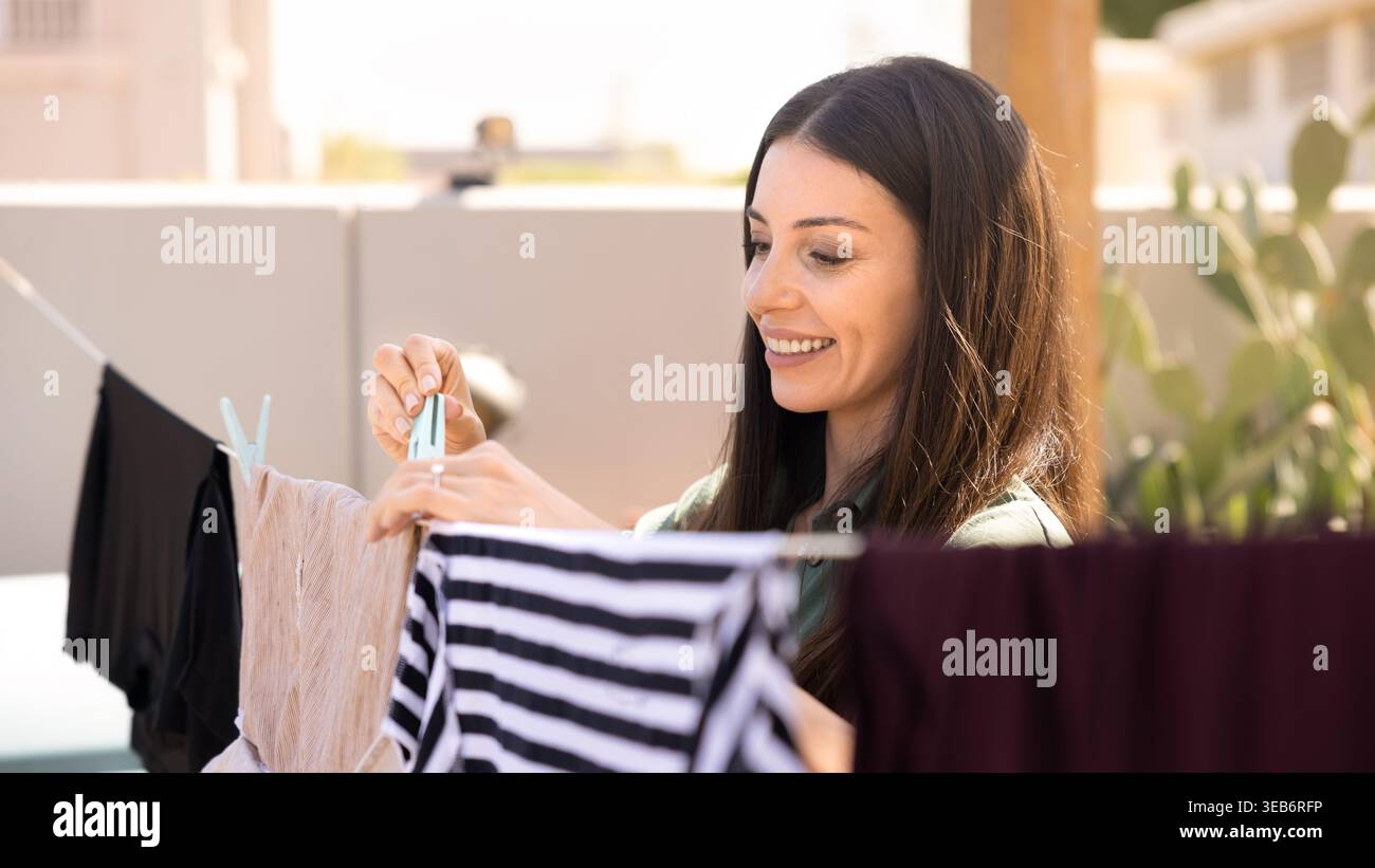 Femme adulte accroche des vêtements fraîchement lavés sur la corde à linge extérieure Banque D'Images
