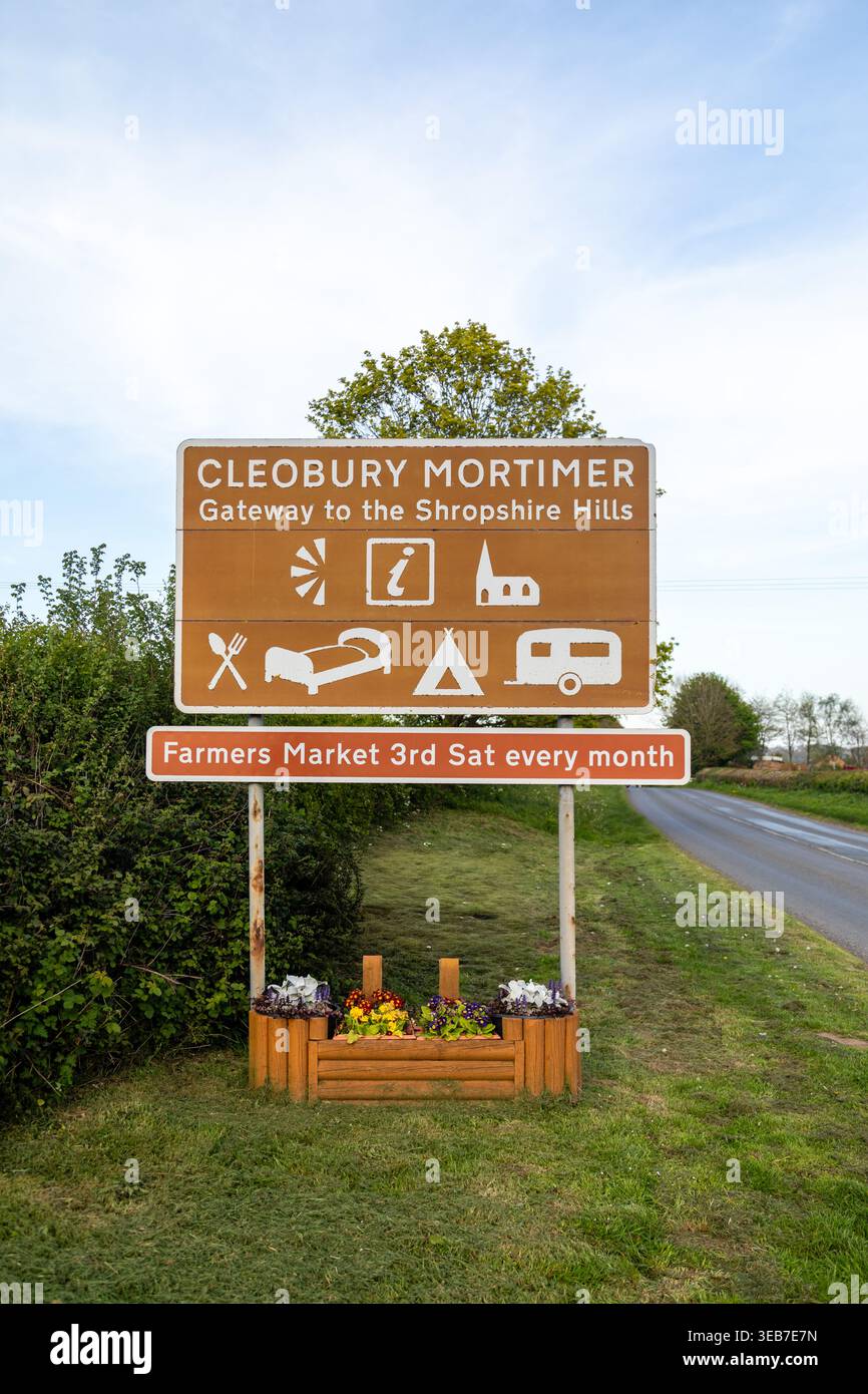 Panneau de bienvenue pour Cleobury Mortimer, Shropshire, Angleterre, avec des icônes des commodités locales et la publicité d'un marché agricole mensuel Banque D'Images