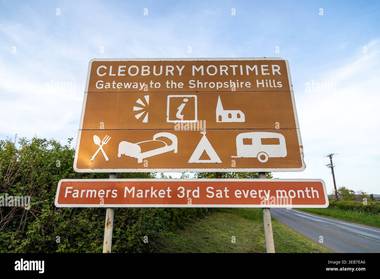 Gros plan du panneau routier Cleobury Mortimer, « Gateway to the Shropshire Hills », montrant des icônes pour les commodités locales et un marché agricole mensuel Banque D'Images