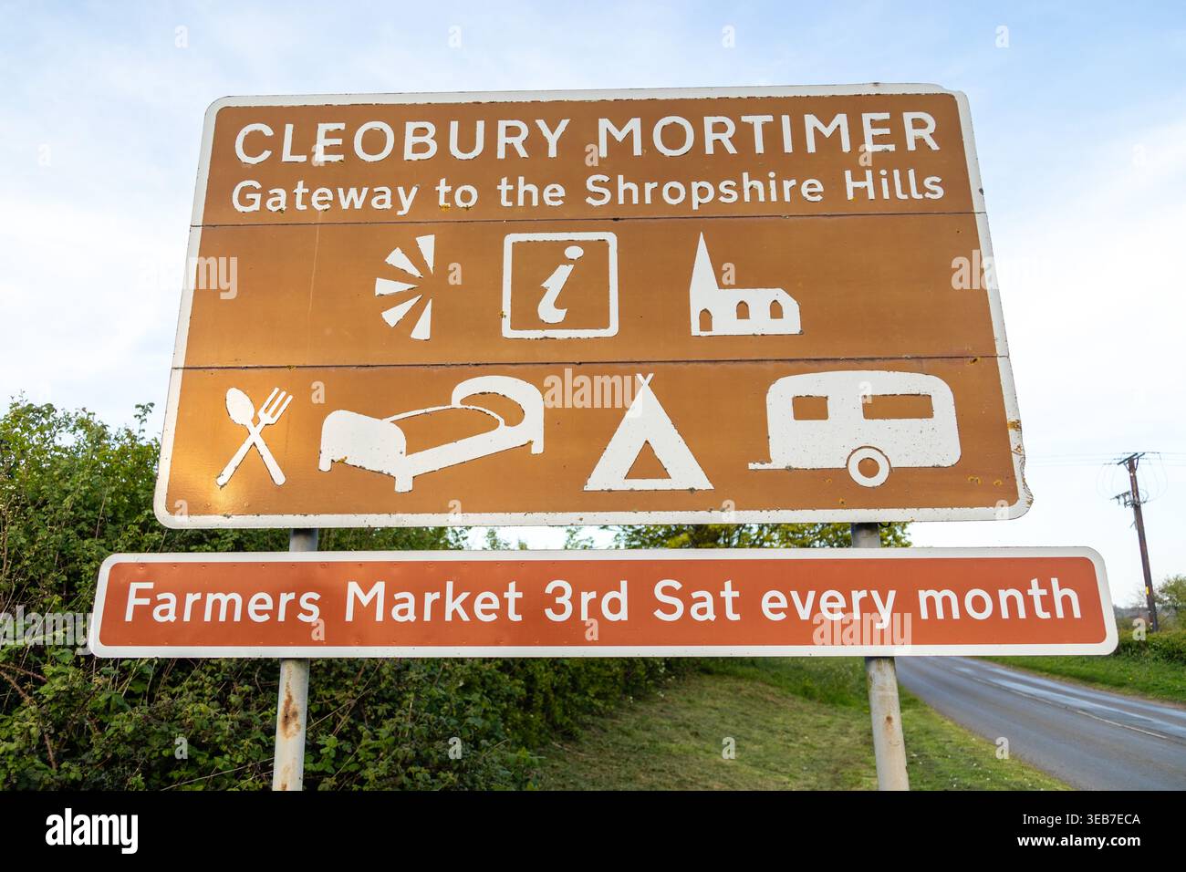 Gros plan du panneau routier Cleobury Mortimer, « Gateway to the Shropshire Hills », montrant des icônes pour les commodités locales et un marché agricole mensuel Banque D'Images