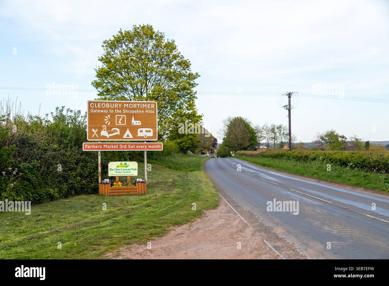 Panneau de bienvenue pour Cleobury Mortimer, Shropshire, Angleterre, avec des icônes des commodités locales et la publicité d'un marché agricole mensuel Banque D'Images