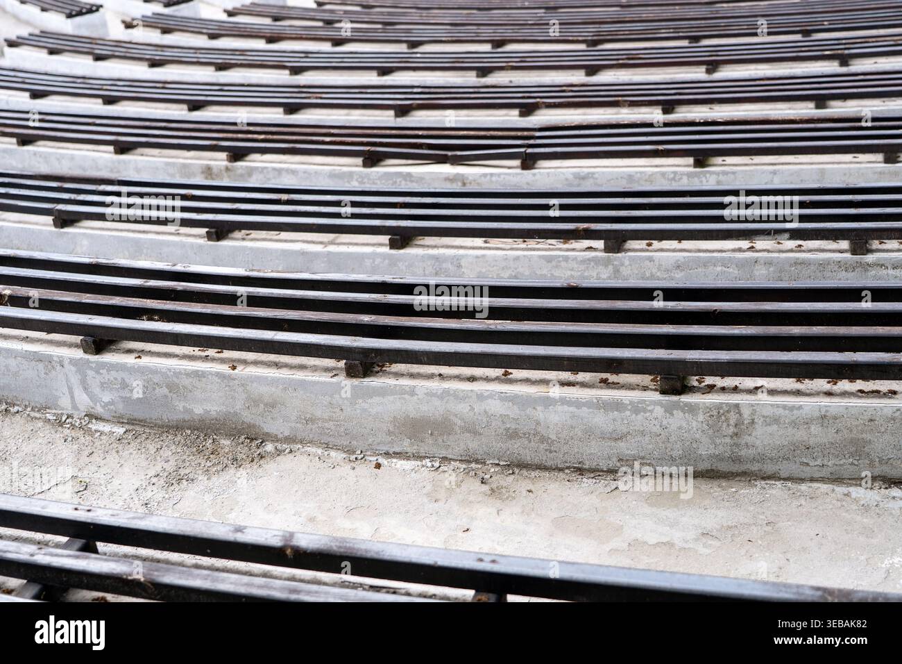 Amphithéâtre en béton vide avec des bancs en bois disposés en rangées géométriques répétitives. Concept : répétition d'objets Banque D'Images