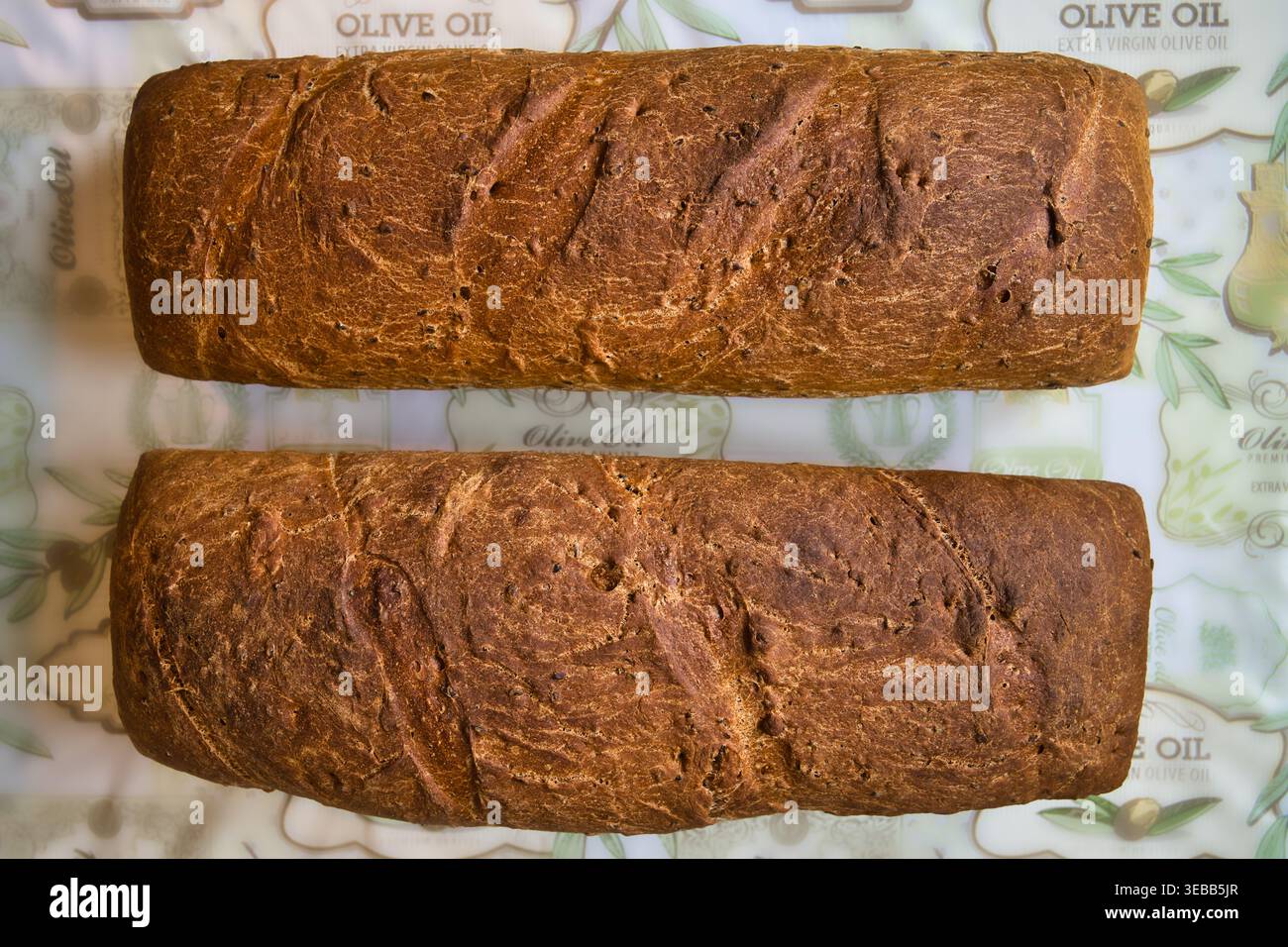 Deux pains faits maison d'épeautre de grains entiers et de pain de seigle sur toile à motifs à l'huile d'olive. Banque D'Images