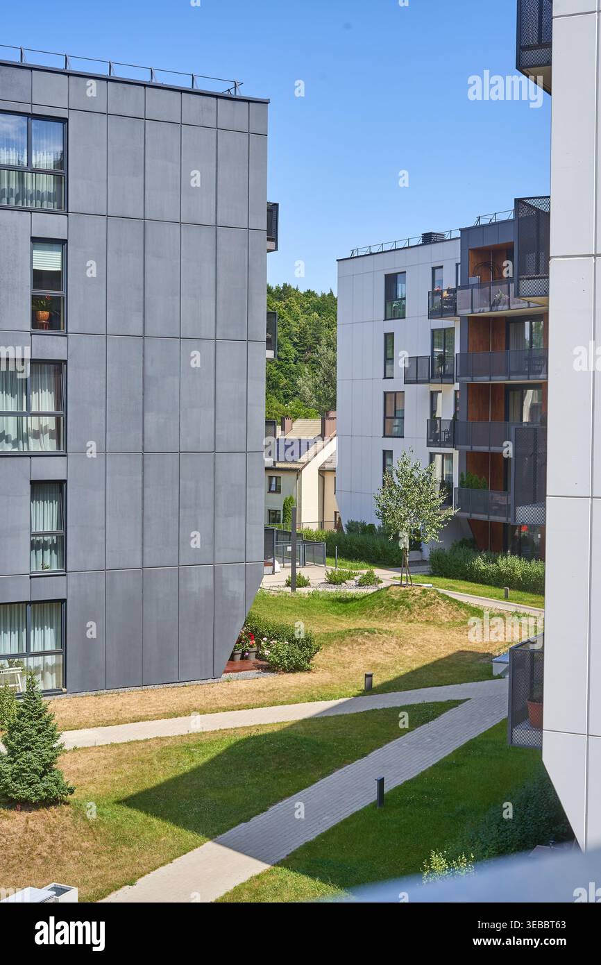 Immeubles d'appartements résidentiels modernes avec une architecture contemporaine présentant des façades en panneaux gris et de grandes fenêtres, entourant un aménagement paysager Banque D'Images