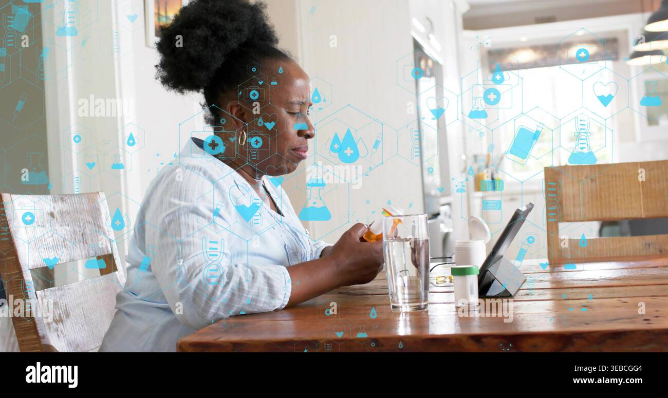 Tenant la bouteille de pilule orange, femme noire portant chemisier vérifiant la tablette à table avec des icônes de santé Banque D'Images