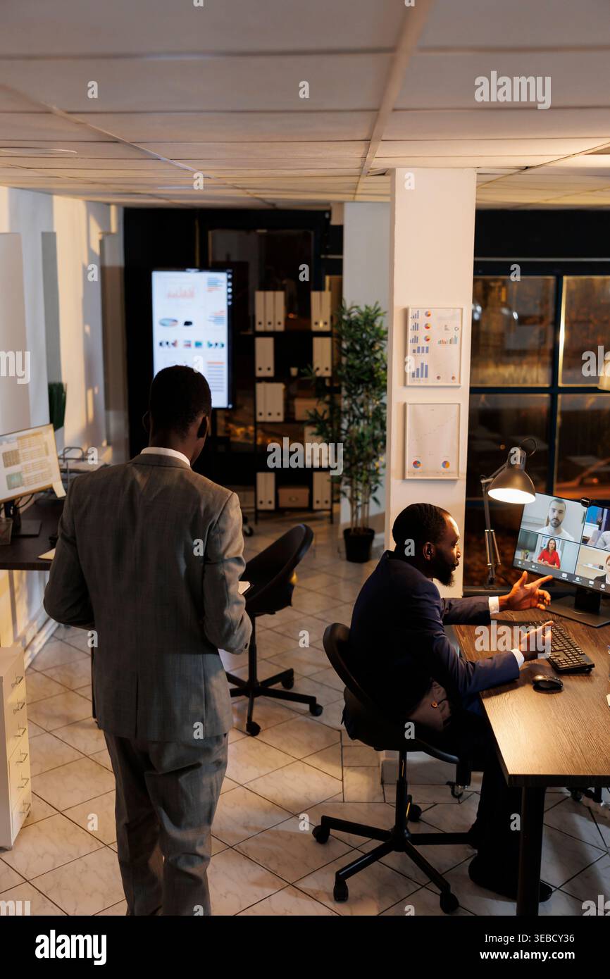 Équipe commerciale discutant des statistiques de marketing pendant la conférence de réunion videocall en ligne, travaillant au fil du temps à la stratégie de l'entreprise dans le bureau de démarrage. Collaborateurs distants préparant un graphique d'investissement Banque D'Images