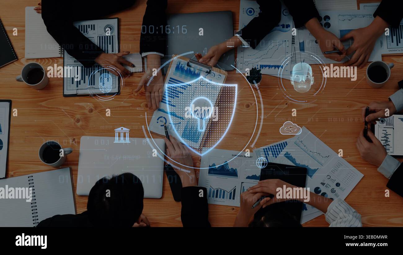 Une équipe commerciale collabore autour d'une table remplie de rapports et d'appareils numériques, en utilisant des outils d'analyse visuelle des données pour améliorer la prise de décision Banque D'Images