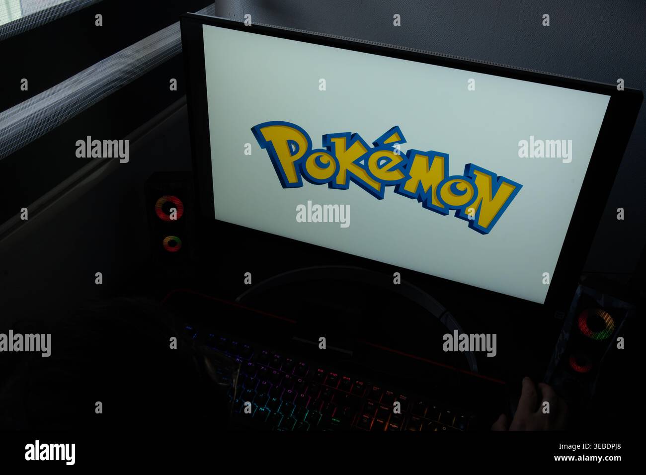 Le logo de la franchise Pokémon Media est affiché sur un écran d'ordinateur dans un environnement de bureau à domicile sombre Banque D'Images