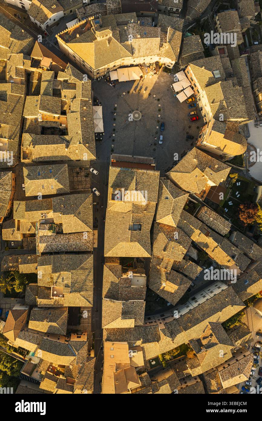 Vue aérienne de la Piazza del Comune circulaire entourée de bâtiments historiques en pierre et de toits carrelés pendant l'heure d'or à Montefalco, Ombrie, Ital Banque D'Images