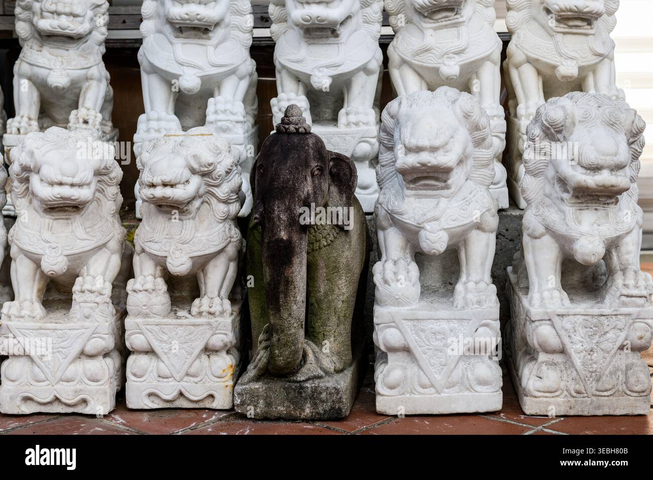 De petites sculptures blanches en pierre en forme de lion et une statue d'éléphant miniature à l'extérieur d'un temple hindou à Singapour. Banque D'Images