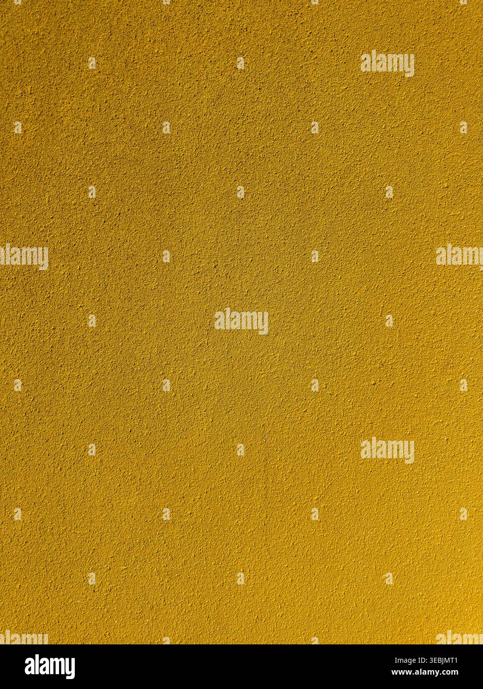 Vue rapprochée d'une surface abrasive jaune éclatante avec une texture granuleuse semblable au sable. L'éclairage uniforme met en évidence le grain fin et les détails poreux o Banque D'Images