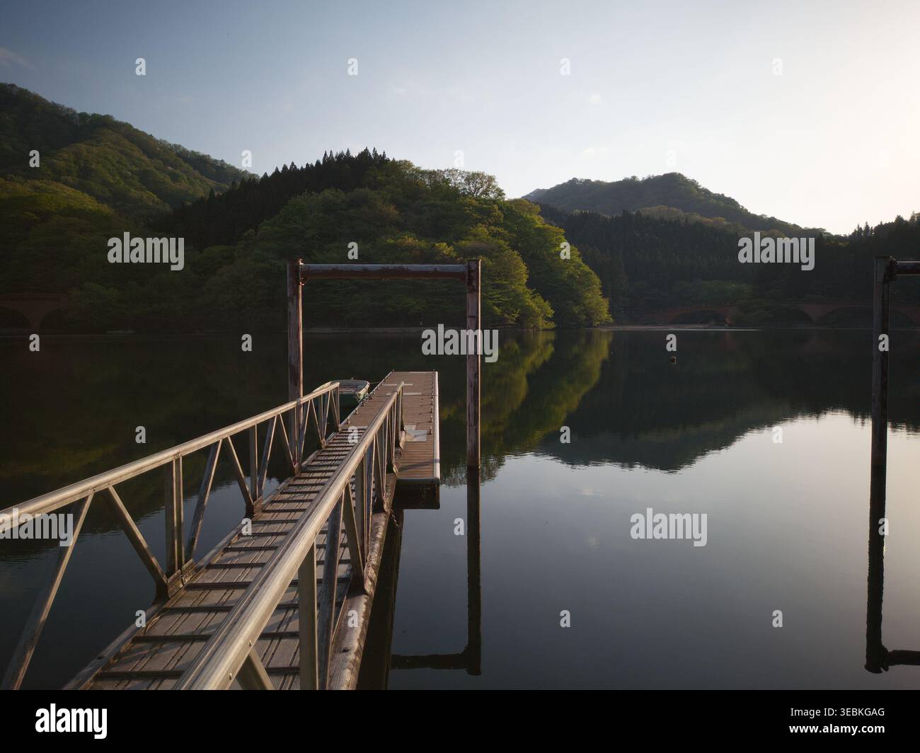 ANNAKA, JAPON - APR 25, 2026 : une jetée en bois s'étendant dans les eaux calmes et parfaitement réfléchissantes du lac Usui entouré de montagnes. Banque D'Images