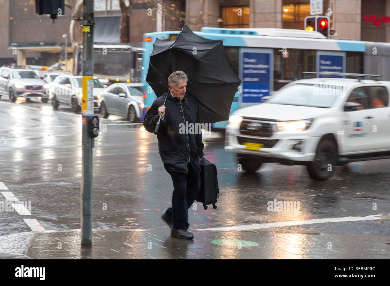 Un homme lutte avec un parapluie dans des conditions humides et venteuses, Sydney, Nouvelle-Galles du Sud, Australie Banque D'Images