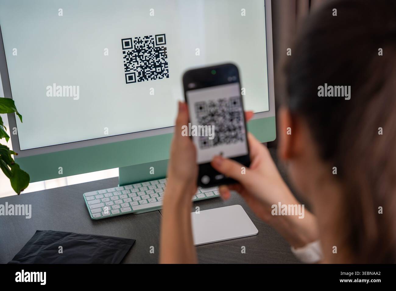 Personne scannant le code QR à partir de l'écran de l'ordinateur avec smartphone à la maison espace de travail. Interaction numérique entre les appareils et concept d'accès aux services en ligne. Banque D'Images