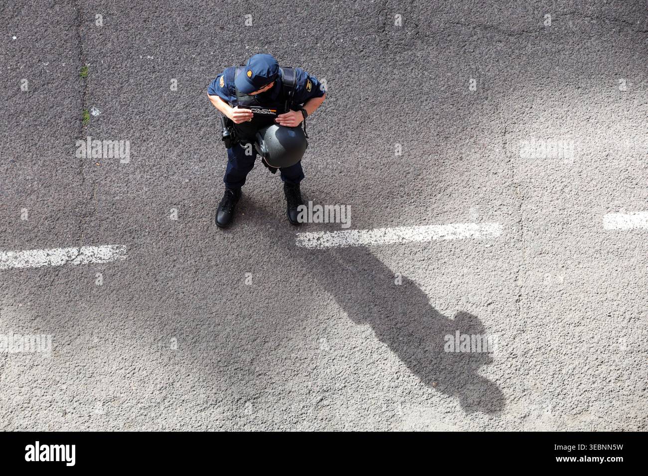 Vue aérienne d'un policier marchant sur une rue urbaine, présence des forces de l'ordre d'en haut Banque D'Images