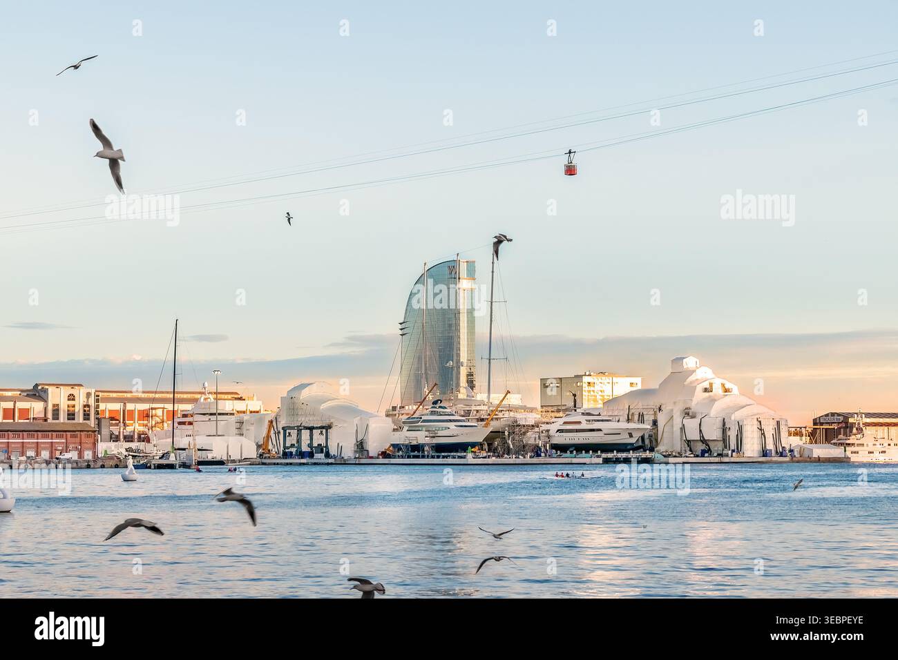 Barcelone, Espagne - 26 novembre 2021 : vue depuis le remblai sur le port de Barcelone, ​​Hotel W et la cabine du téléphérique au-dessus d'eux. Les mouettes volent Banque D'Images