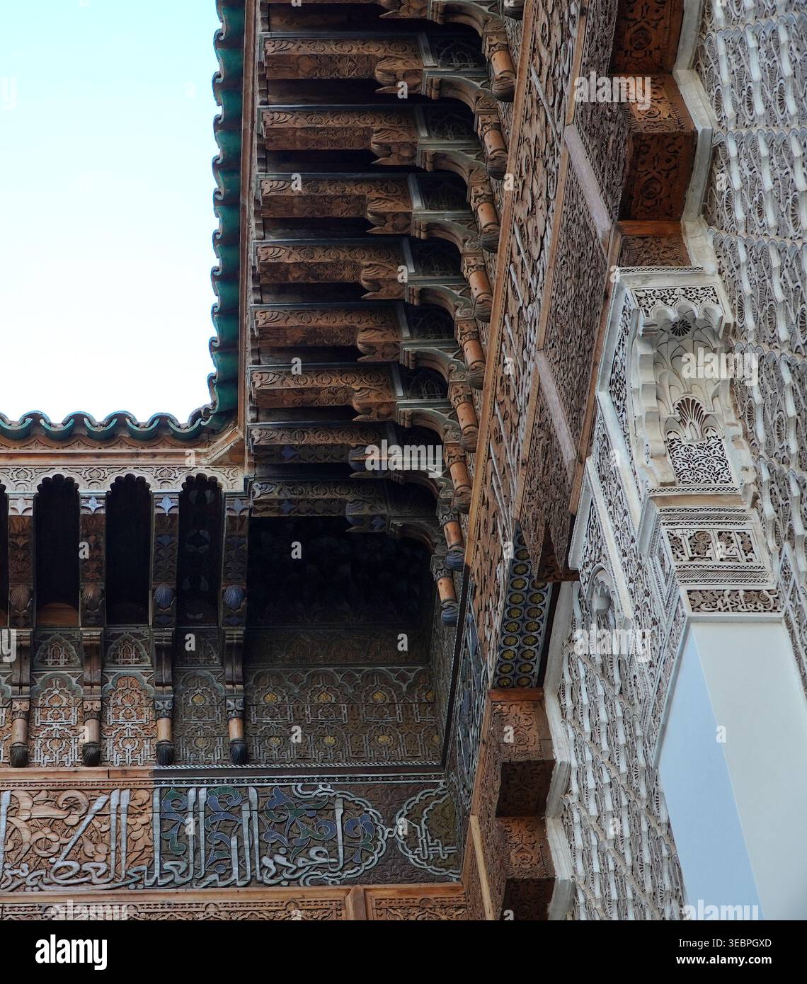 Corbeaux en bois sculpté ornés, arabesques en stuc et frise de calligraphie arabe dans une madrasa marocaine historique, Marrakech. Banque D'Images