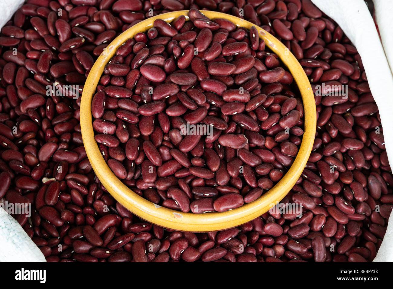 Séchez les haricots rouges dans un bol en céramique à l'intérieur d'un grand sac au marché Banque D'Images