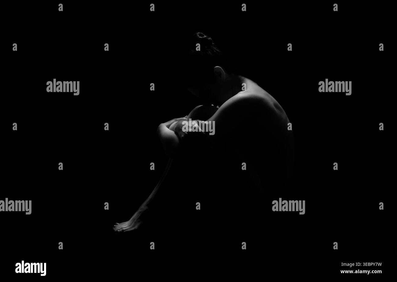 Figure dans un espace sombre transmet l'émotion à travers le langage corporel et la posture Banque D'Images