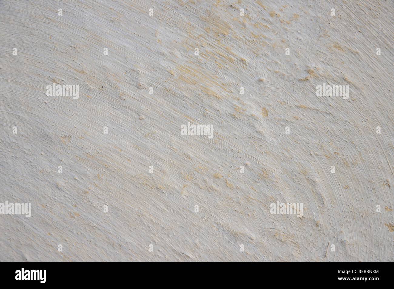 Texture murale en plâtre blanc avec des nuances jaunes subtiles et des détails de coup de pinceau rugueux, idéale pour les décors graphiques et les superpositions minimalistes. Banque D'Images