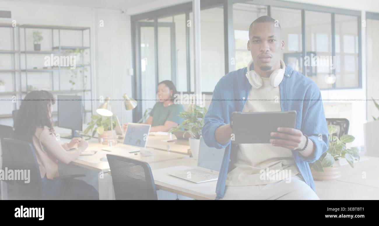 Tenant la tablette, portant des écouteurs, homme portant une chemise beige assis sur le bureau au bureau, espace de copie Banque D'Images