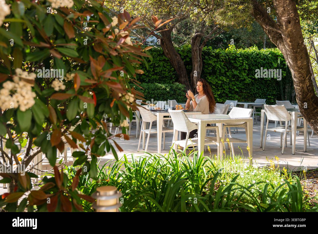 Terrasse de jardin salle à manger à Antibes, France avec chaises blanches et arbres Banque D'Images