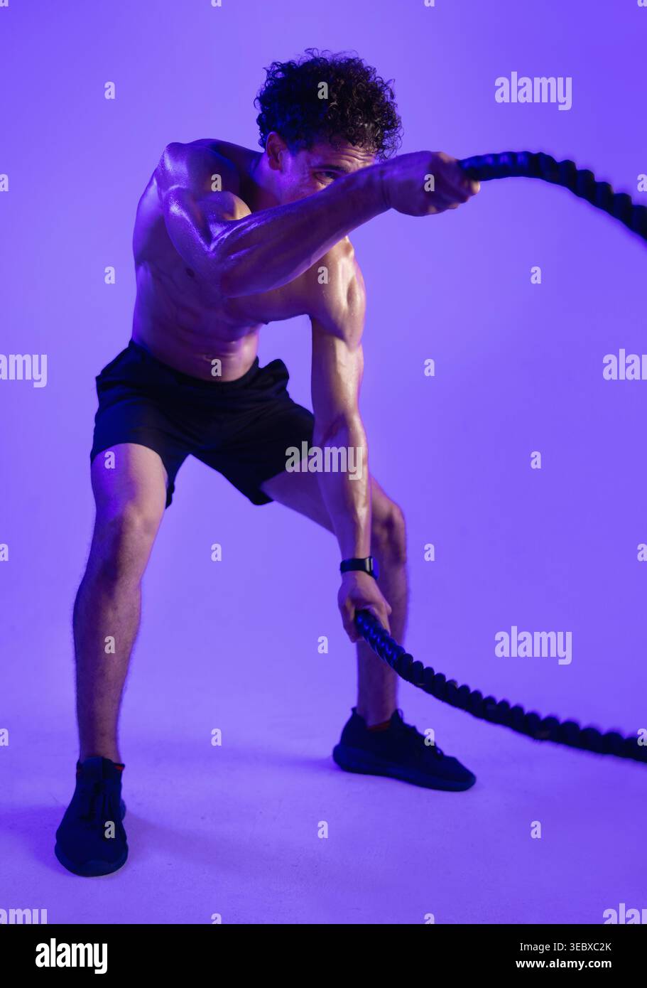 Homme, cordes de combat et fitness en studio pour l'entraînement, le muscle et le défi sur fond violet. Personne, cordon et sueur avec entraînement intense, exercice Banque D'Images