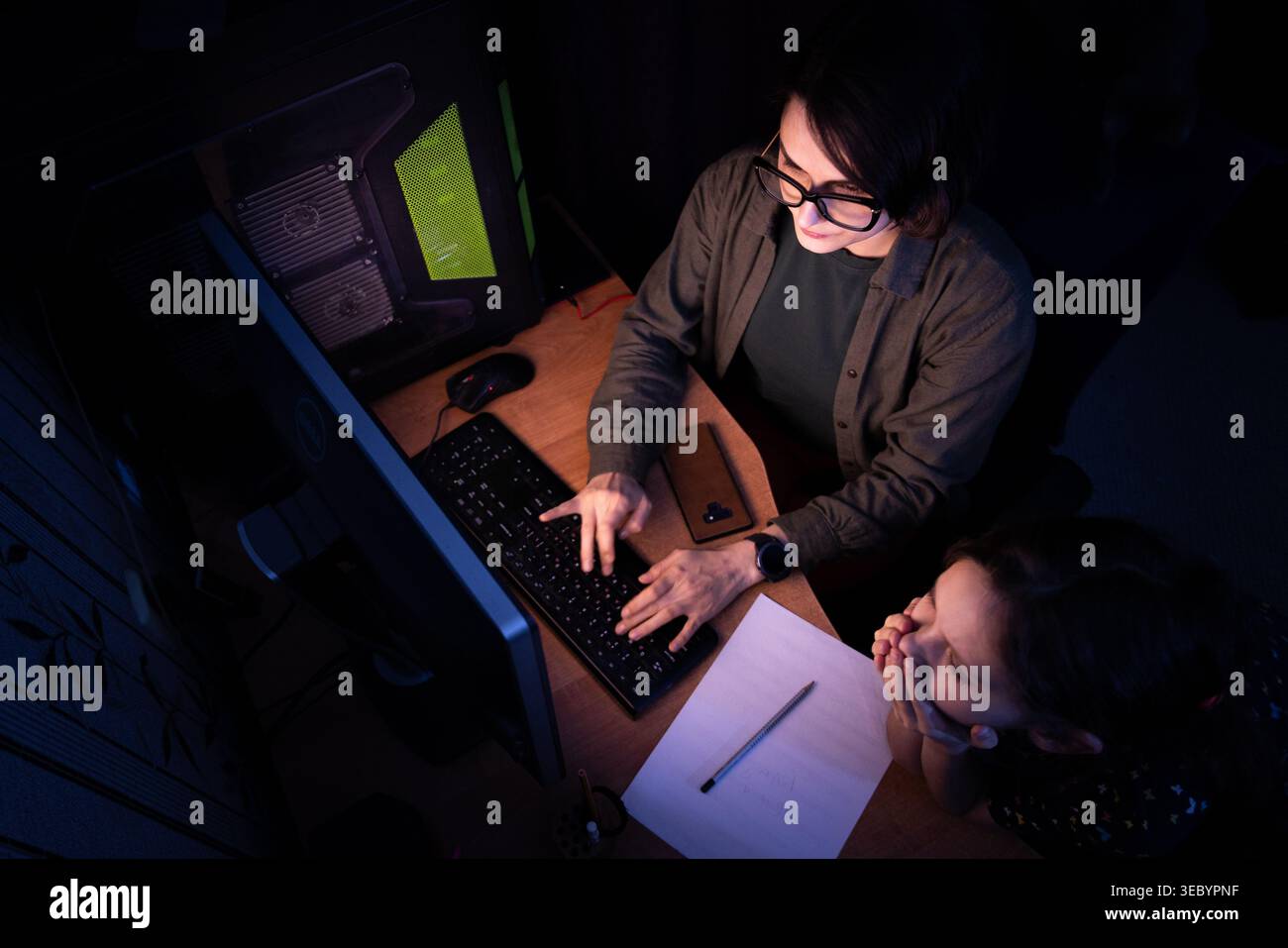 Maman qui travaille avec enfant à la réception de nuit Banque D'Images