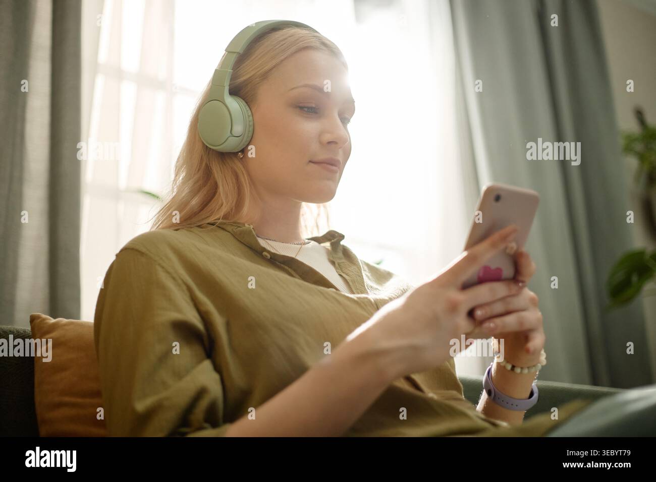 Femme adulte utilisant smartphone et casque pour le streaming audio Banque D'Images