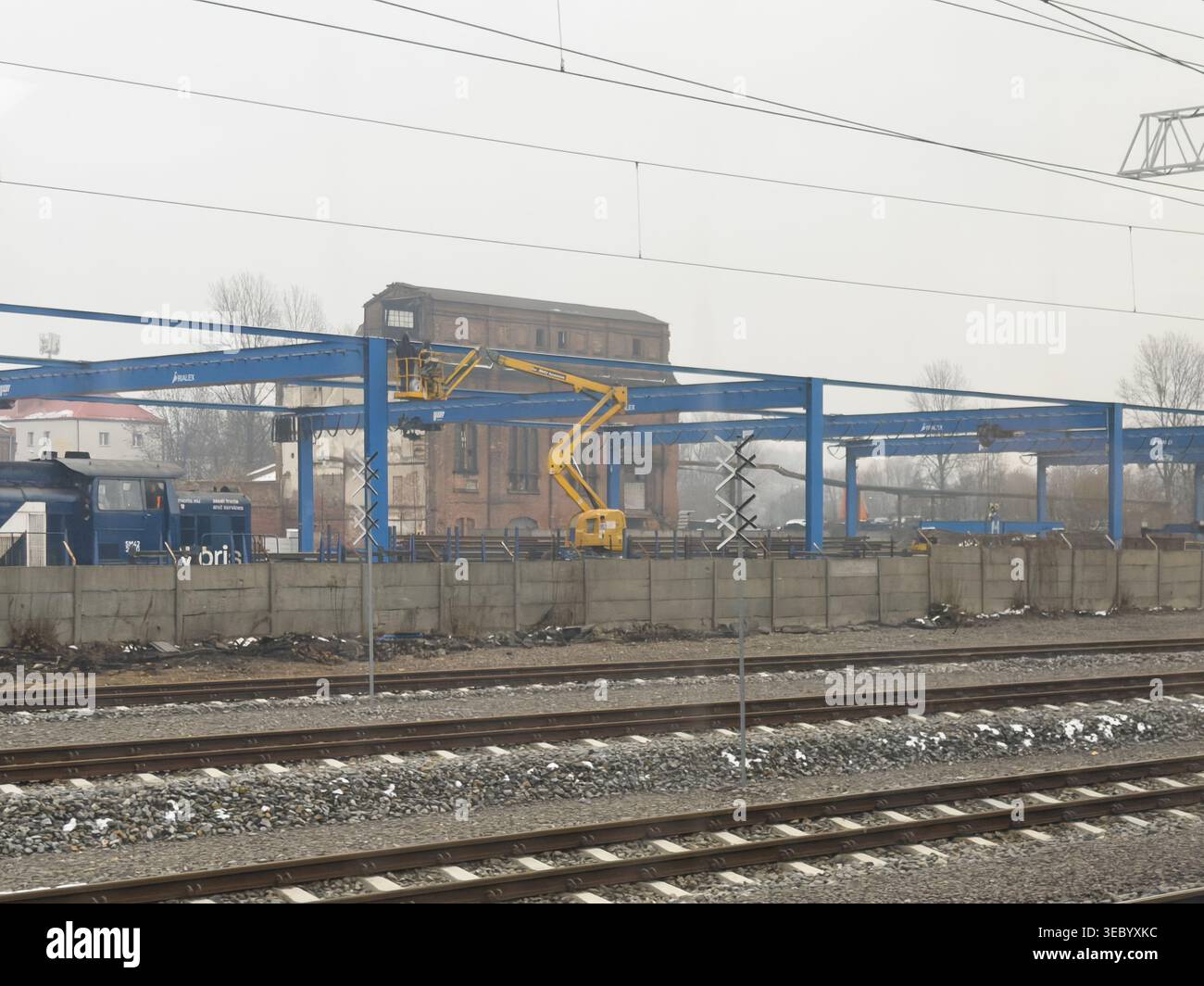 Katowice, Pologne - 3 décembre 2025 : le cueilleur articulé de cerises travaille sur des cadres métalliques bleus sur le site du dépôt ferroviaire pour la maintenance industrielle lourde Banque D'Images