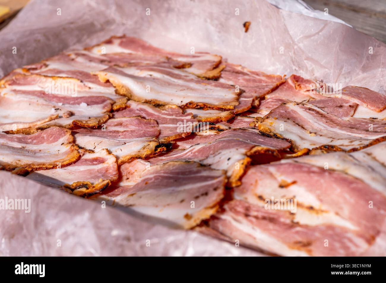 Bacon grillé en tranches détaillées sur papier. Aliments traditionnels à base de viande de porc en gros plan Banque D'Images