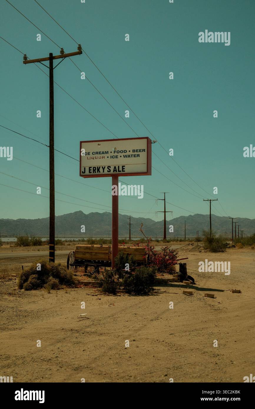 Panneau de stand saccadé isolé au bord de la route dans le désert californien avec des lignes électriques et des montagnes en arrière-plan. Banque D'Images