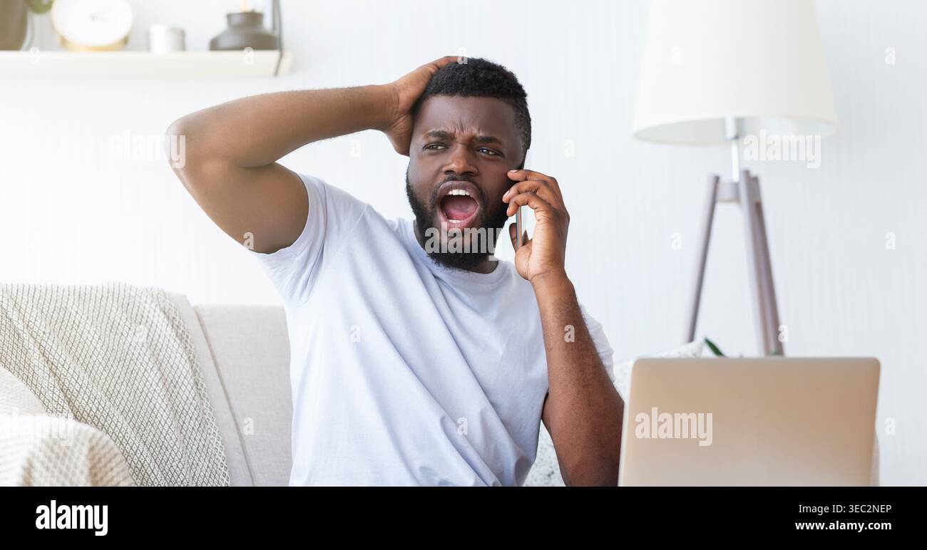 L'homme exprime sa frustration en parlant au téléphone au bureau à domicile pendant les heures de jour Banque D'Images